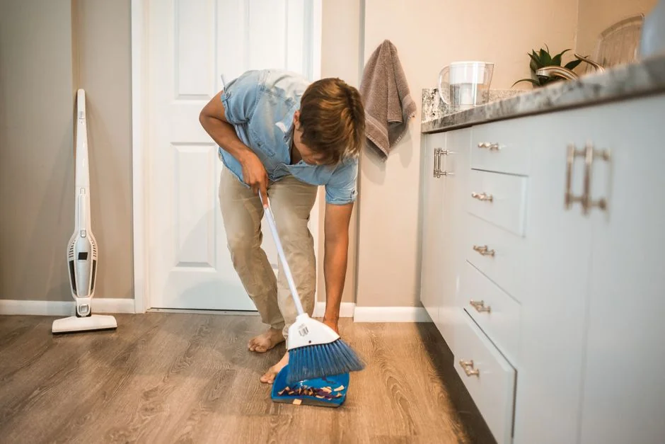 A man in coveralls is cleaning a large window inside a stylish, modern home interior.