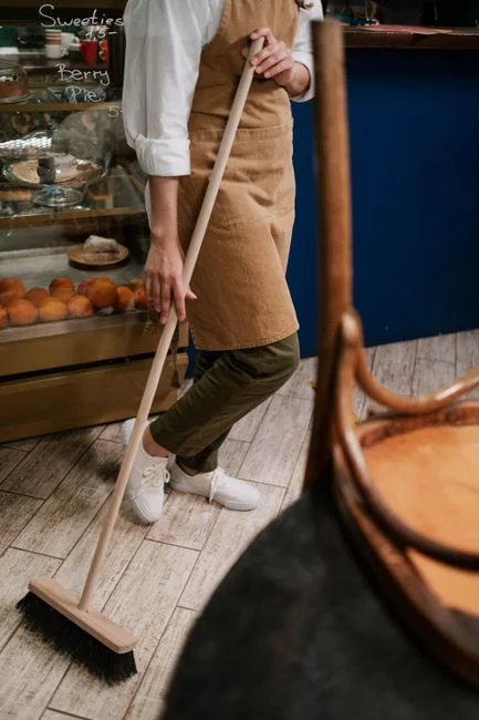 A professional cleaner in protective gear vacuuming the floor in a modern living room.